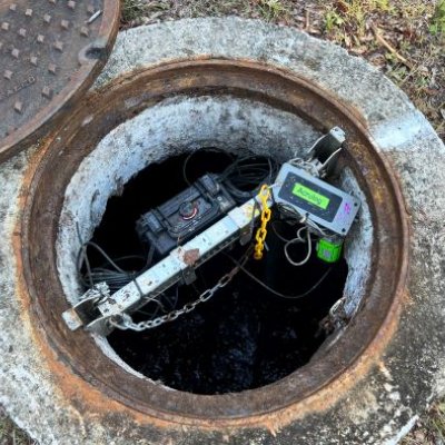 some wires and tech equipment sits inside a concrete-surrounded hole in the ground